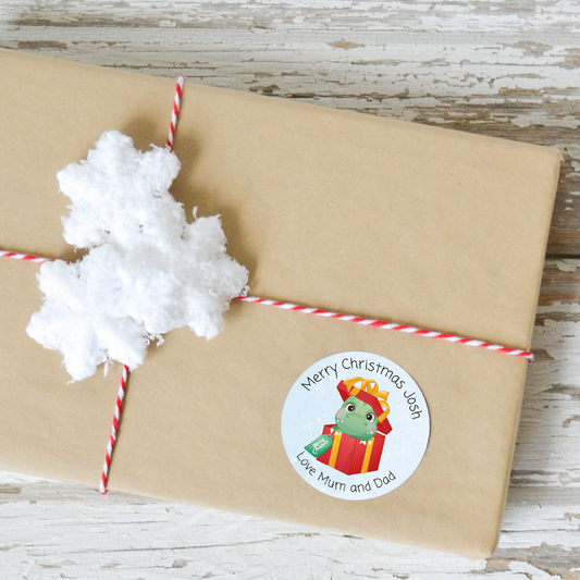 Personalised round Christmas sticker with a dinosaur in a present box